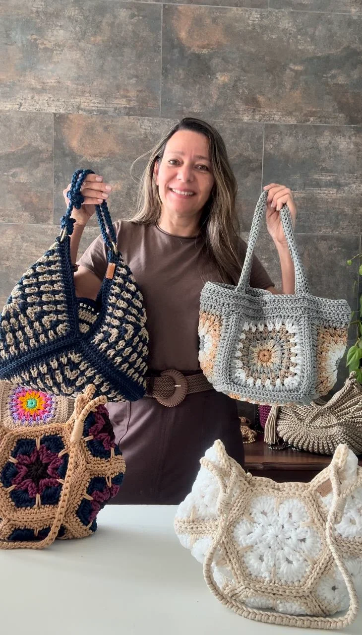 Kelly Paulino, criadora da Coleção Bolsas de Crochê de Verão, segurando bolsas de crochê autorais